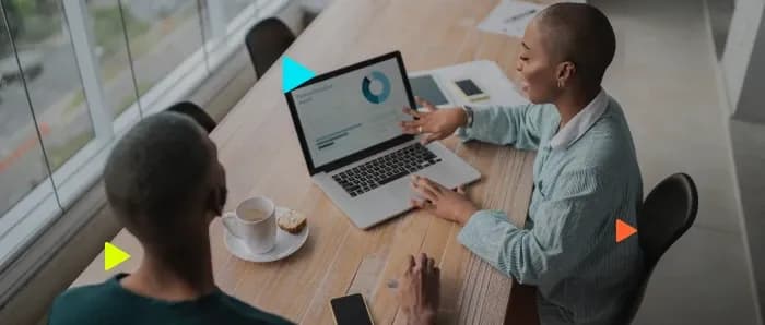 Mulher mostrando gráficos no notebook para um colega, ilustrando a integração VExpenses no sistema Omie.