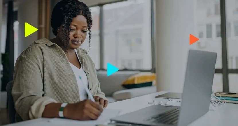Mulher escrevendo em mesa com computador