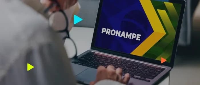 Pessoa usando laptop com logo do Pronampe visível.