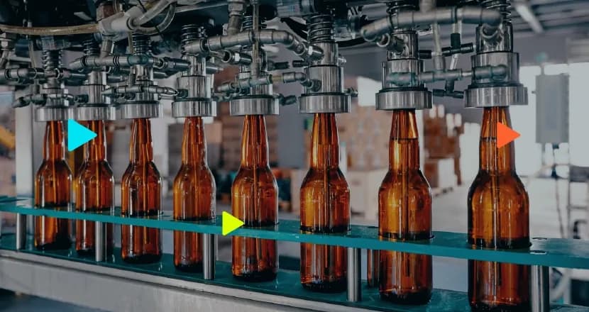 Linha de produção industrial com máquina enchendo garrafas de vidro marrom em uma esteira, ilustrando a aplicação do imposto seletivo na indústria de bebidas.
