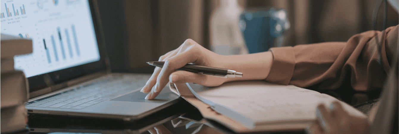 Relatório financeiro: pessoa com caderno, notebook e caneta