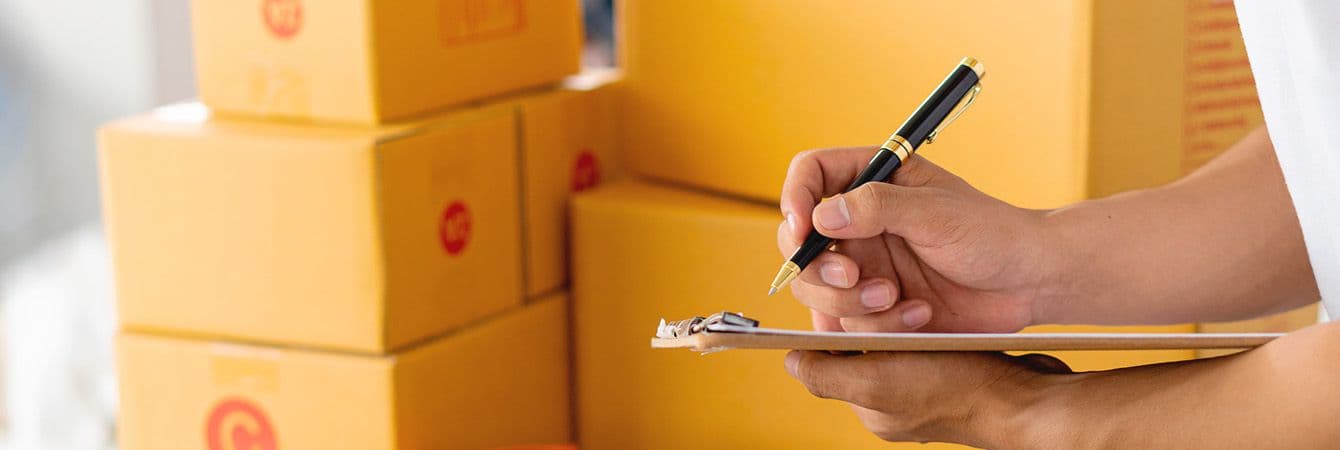Estoque mínimo: pessoa assinando papel perto de caixas