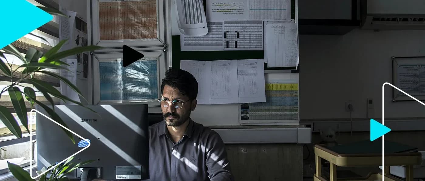 Empreendedor trabalhando no computador em escritório com planilhas na parede