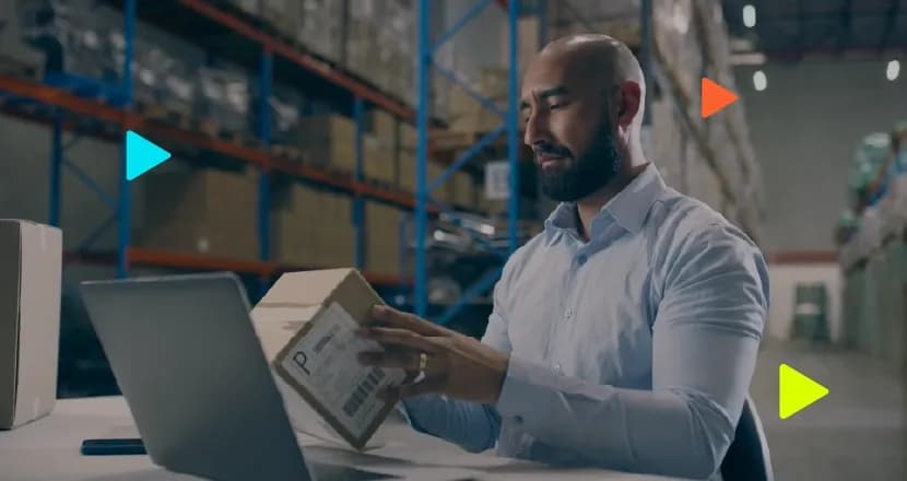 Homem abrindo caixa em armazém com laptop
