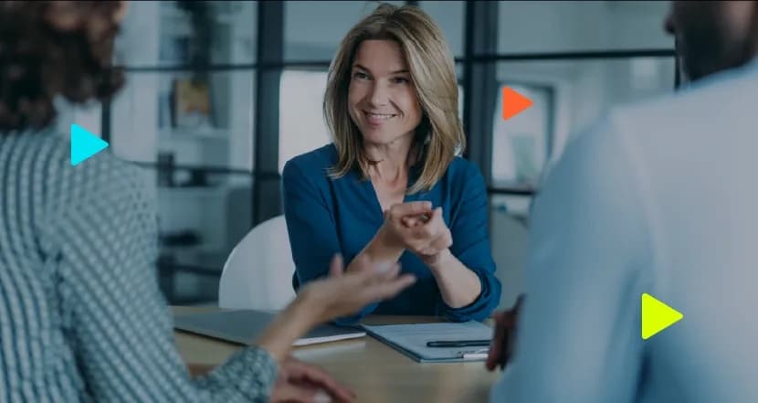 Consultora sorridente conversando e orientando clientes em uma mesa de reunião no escritório.