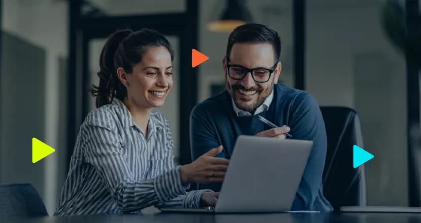 Dois profissionais sorridentes analisam juntos um notebook no escritório, ilustrando a gestão corporativa de múltiplos CNPJs.