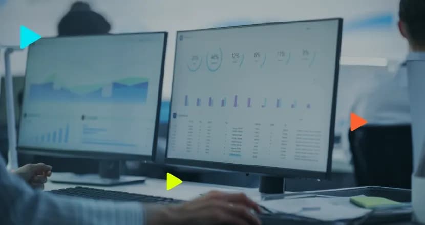 Dois monitores que apresentam gráficos e dados em planilhas