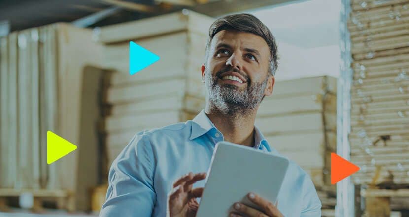 Homem sorridente com tablet em ambiente de trabalho.