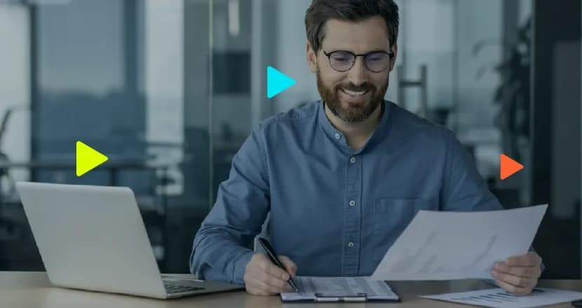 Homem sorrindo analisando documentos em escritório moderno.