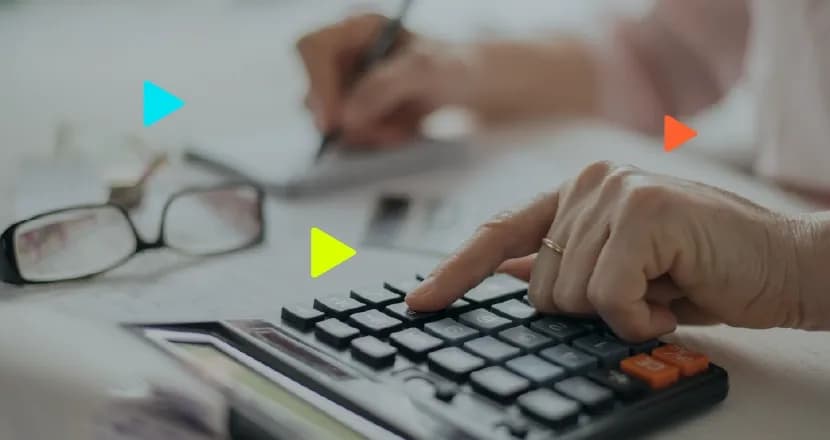 Mão usando calculadora e anotando em caderno