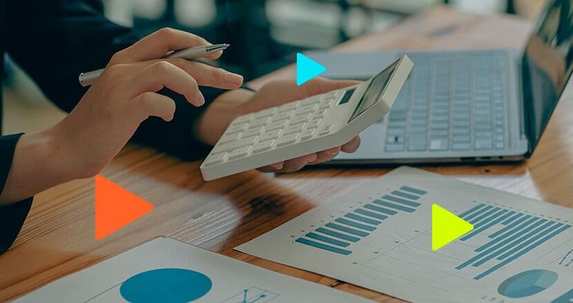 Mãos utilizando calculadora e gráficos em mesa
