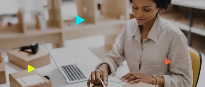 Mulher organizando embalagem em mesa de trabalho.