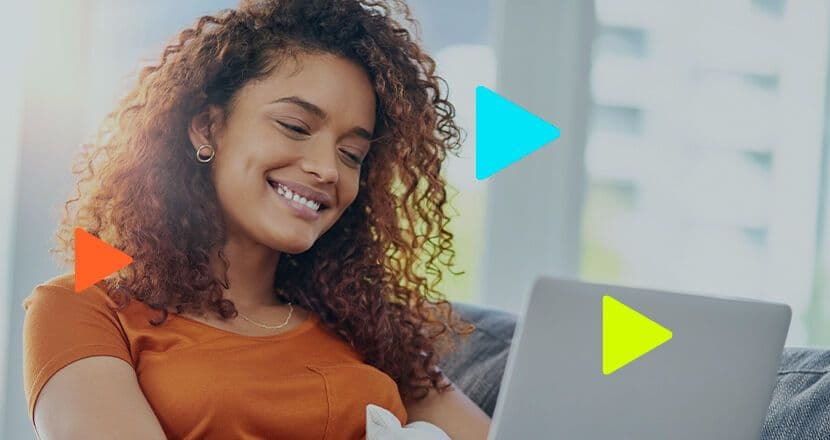 Mulher sorrindo enquanto usa laptop em ambiente aconchegante