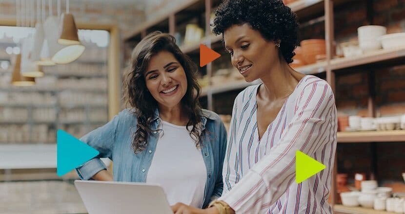 Duas mulheres sorrindo enquanto trabalham em um laptop.