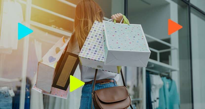 Pessoa segurando sacolas de compras do lado de fora de uma loja.