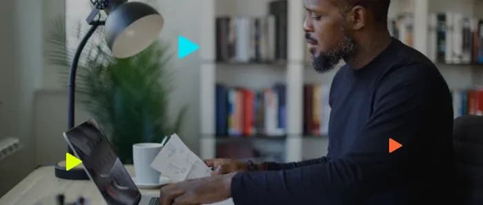 Homem analisando documentos com seu notebook na mesa.