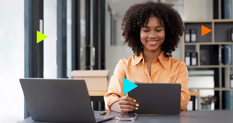 Régua de cobrança: mulher sorrindo com tablet e notebook em mesa
