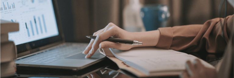 Relatório financeiro: pessoa com caderno, notebook e caneta