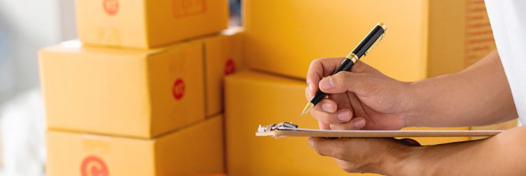 Estoque mínimo: pessoa assinando papel perto de caixas
