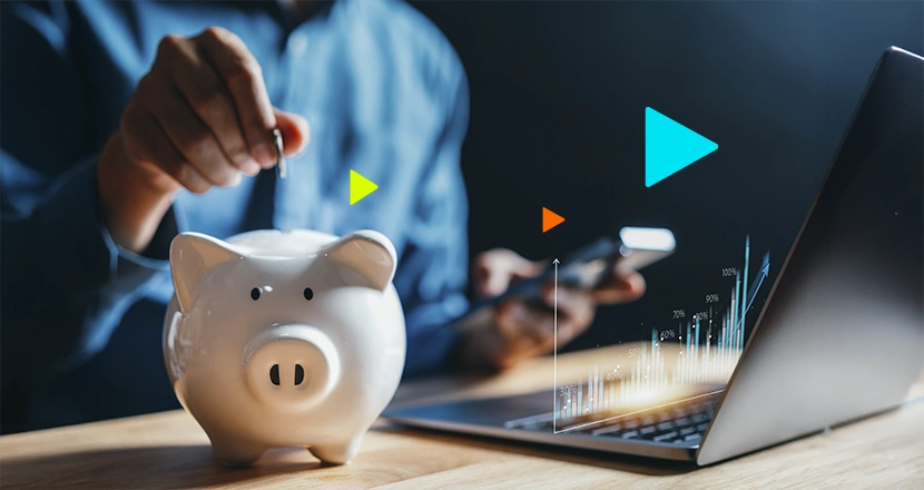 Empreendedor colocando moedas no cofrinho em formato de porquinho, ao lado um notebook para representar o sistema de fluxo de caixa