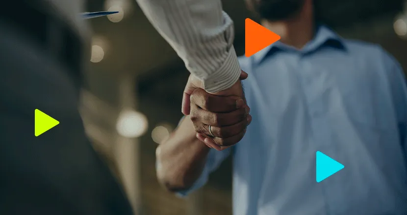 Homens de camisa social apertando as mãos em plano detalhado com ícones geométricos coloridos sobrepostos.