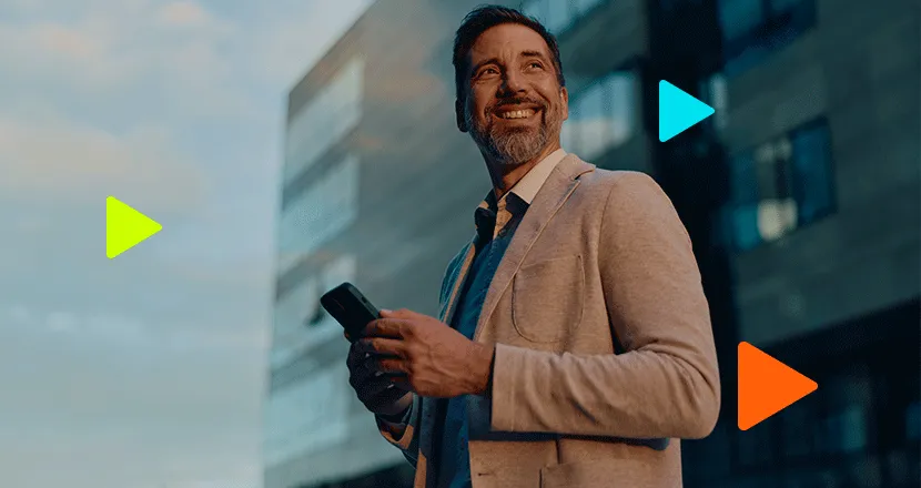 Homem de negócios sorridente segurando smartphone em frente a edifício moderno.