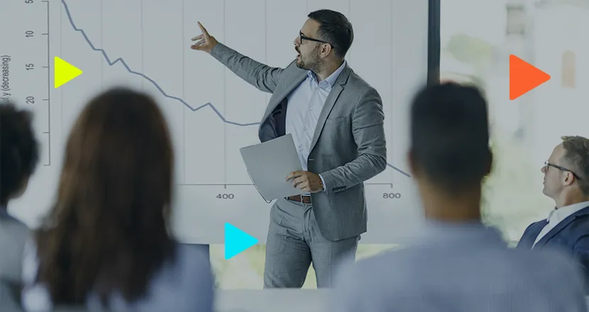 Apresentador em reunião com gráfico ao fundo
