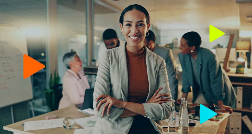 Líder feminina sorridente de braços cruzados em escritório moderno.