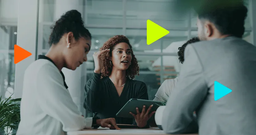 Líder de equipe explicando conceitos com tablet em reunião colaborativa.
