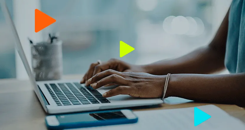 Profissional trabalhando em laptop com smartphone ao lado.