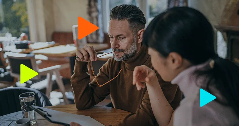 Duas pessoas em reunião de negócios discutindo contrato ou plano de ação sobre mesa de madeira.