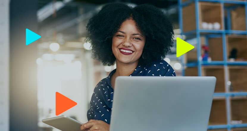 Mulher sorridente usando laptop e tablet no escritório.