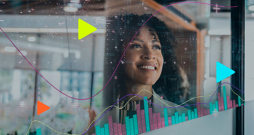 Mulher sorrindo diante de gráficos em uma tela.