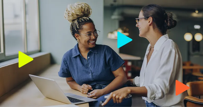 Duas mulheres conversando sobre trabalho em um laptop.