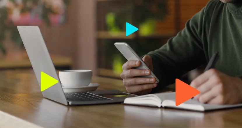 Pessoa trabalhando com notebook e celular na mesa.