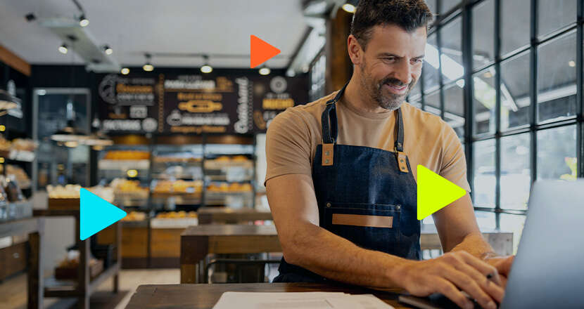 Homem sorridente trabalhando em cafeteria com laptop
