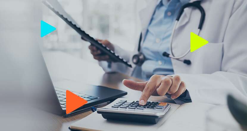 Médico usando calculadora e laptop.