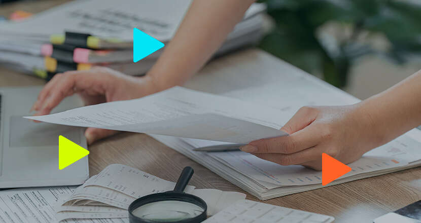 Pessoa organizando documentos em mesa de trabalho.