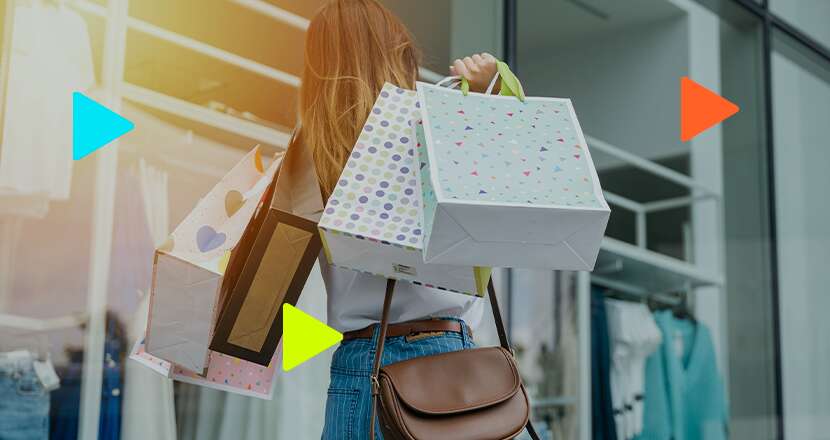 Pessoa segurando sacolas de compras do lado de fora de uma loja.