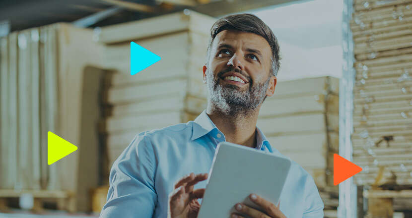 Homem sorridente com tablet em ambiente de trabalho.